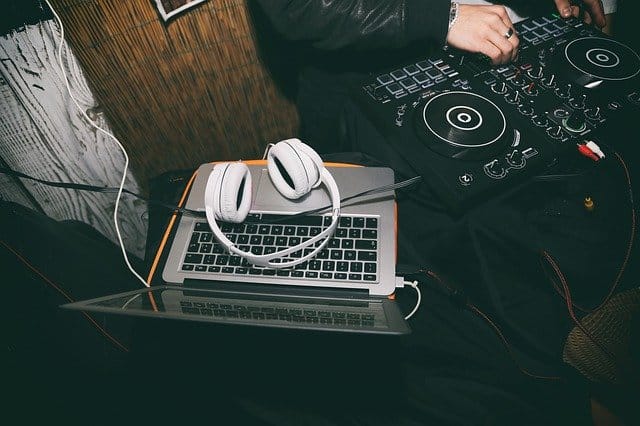 Someone with a DJ controller, laptop, and headphones