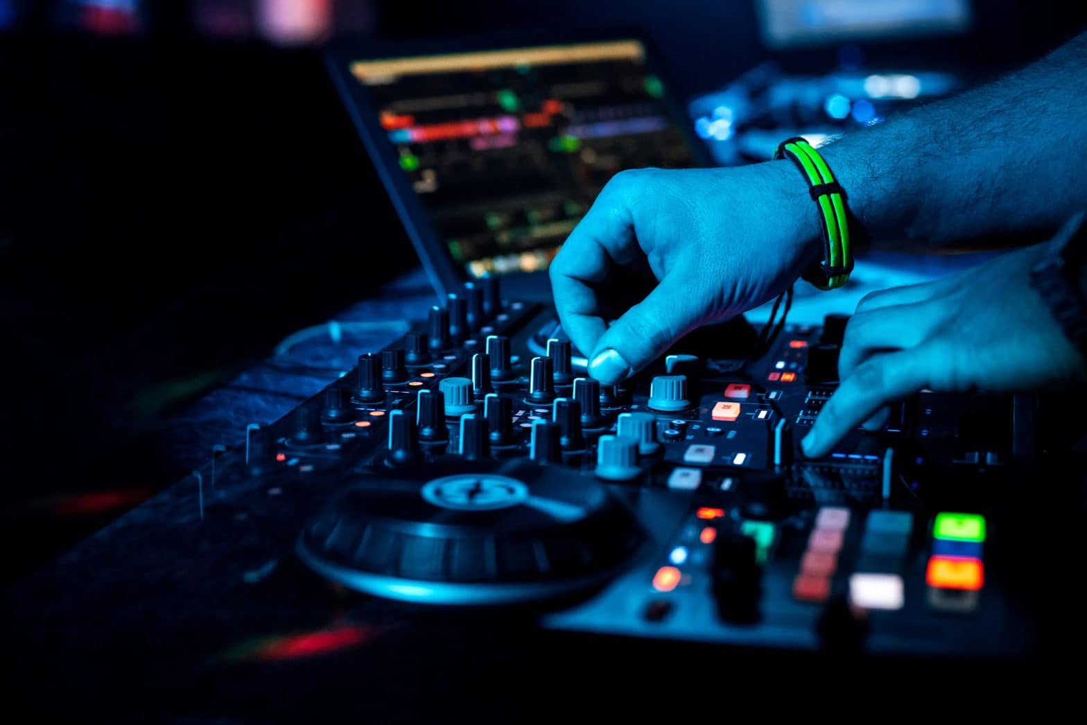 DJ hand mixes electronic music on a professional mixer in a nightclub at a concert